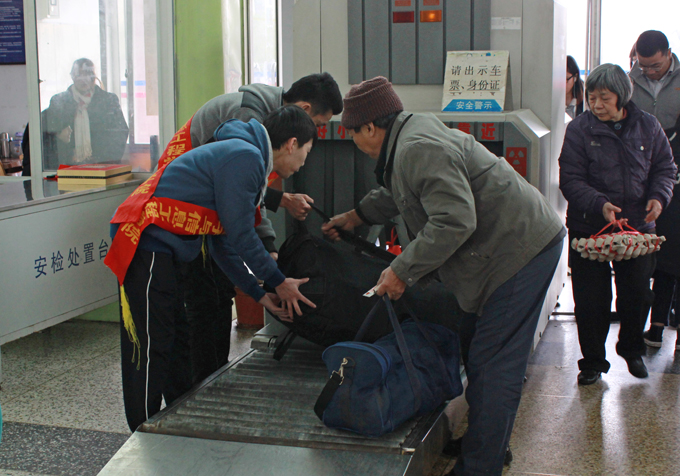 志愿者在安检处帮乘客们提起行李